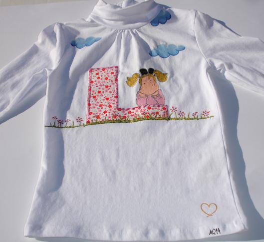 Otra vista de la camiseta con inicial de nombre aplicada y dibujos pintados a mano, para Laia.