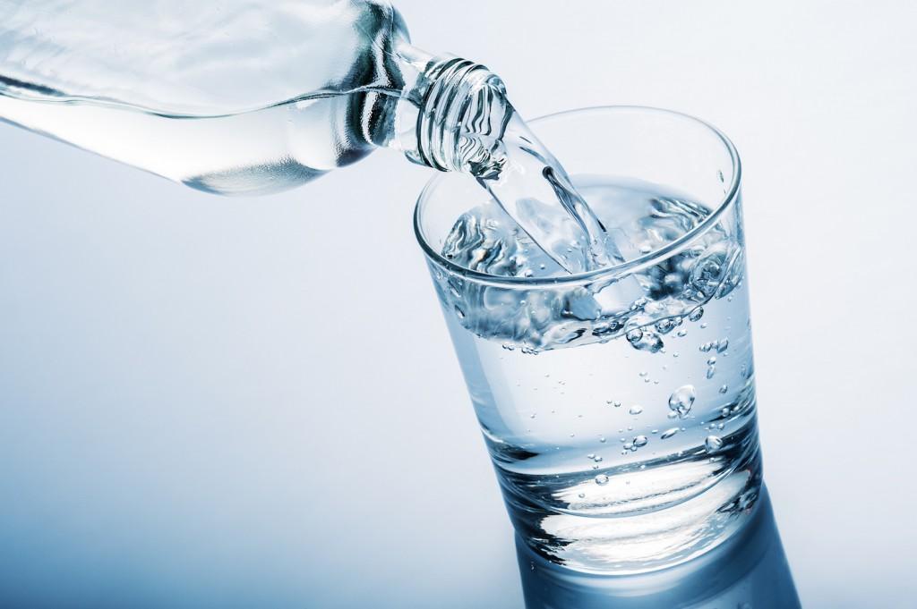 Sirviendo agua desde una botella en un vaso