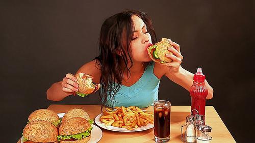mujer comiendo una hamburguesa