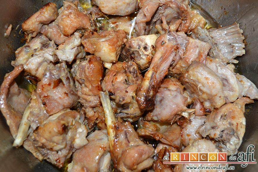 Conejo al ajillo, removemos todo bien dejando que evapore el alcohol y se dore bien todos los trozos de conejo