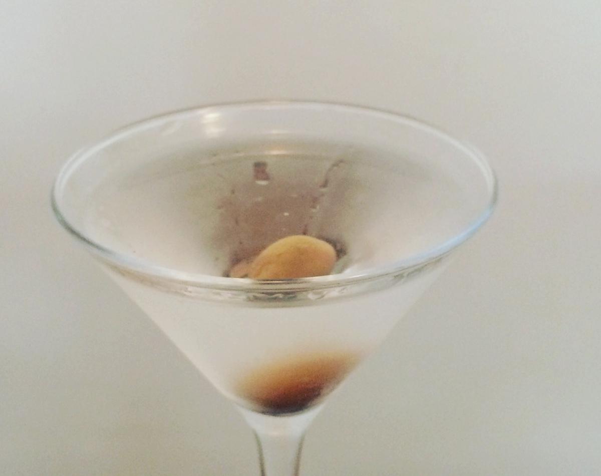Sirviendo el coctel Dry Martini con aceituna