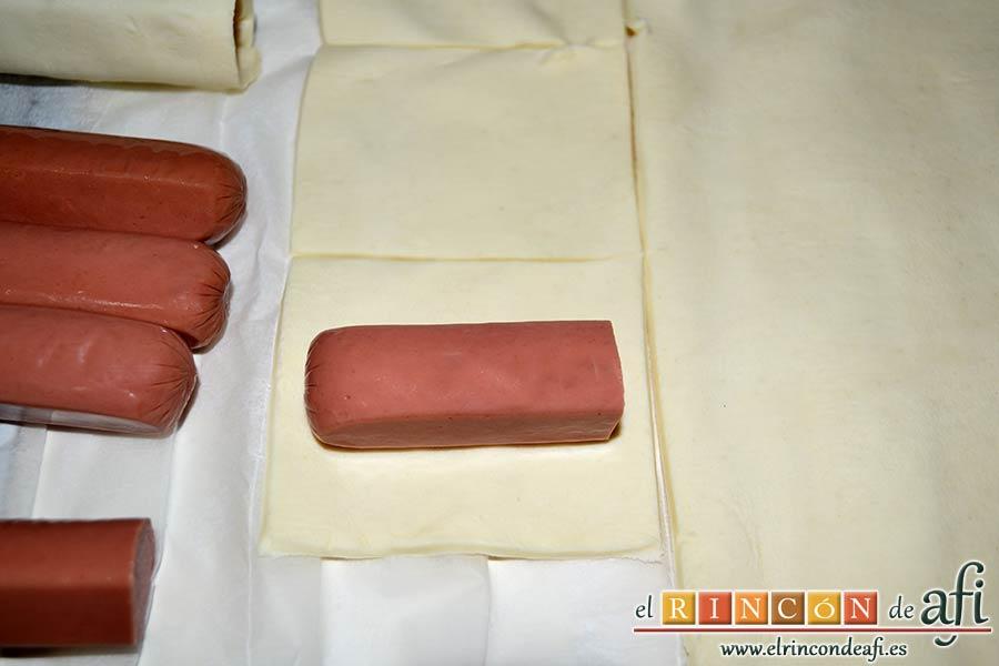 Aperitivo de hojaldre con salchichas o bacon, cortar las salchichas por la mitad y colocarla sobre un rectángulo de hojaldre