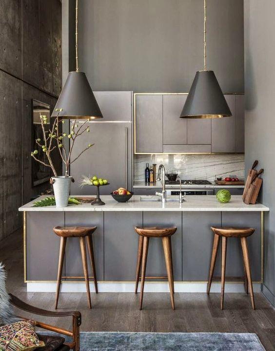 Cocina en gris y dorado con lámparas que iluminan barra
