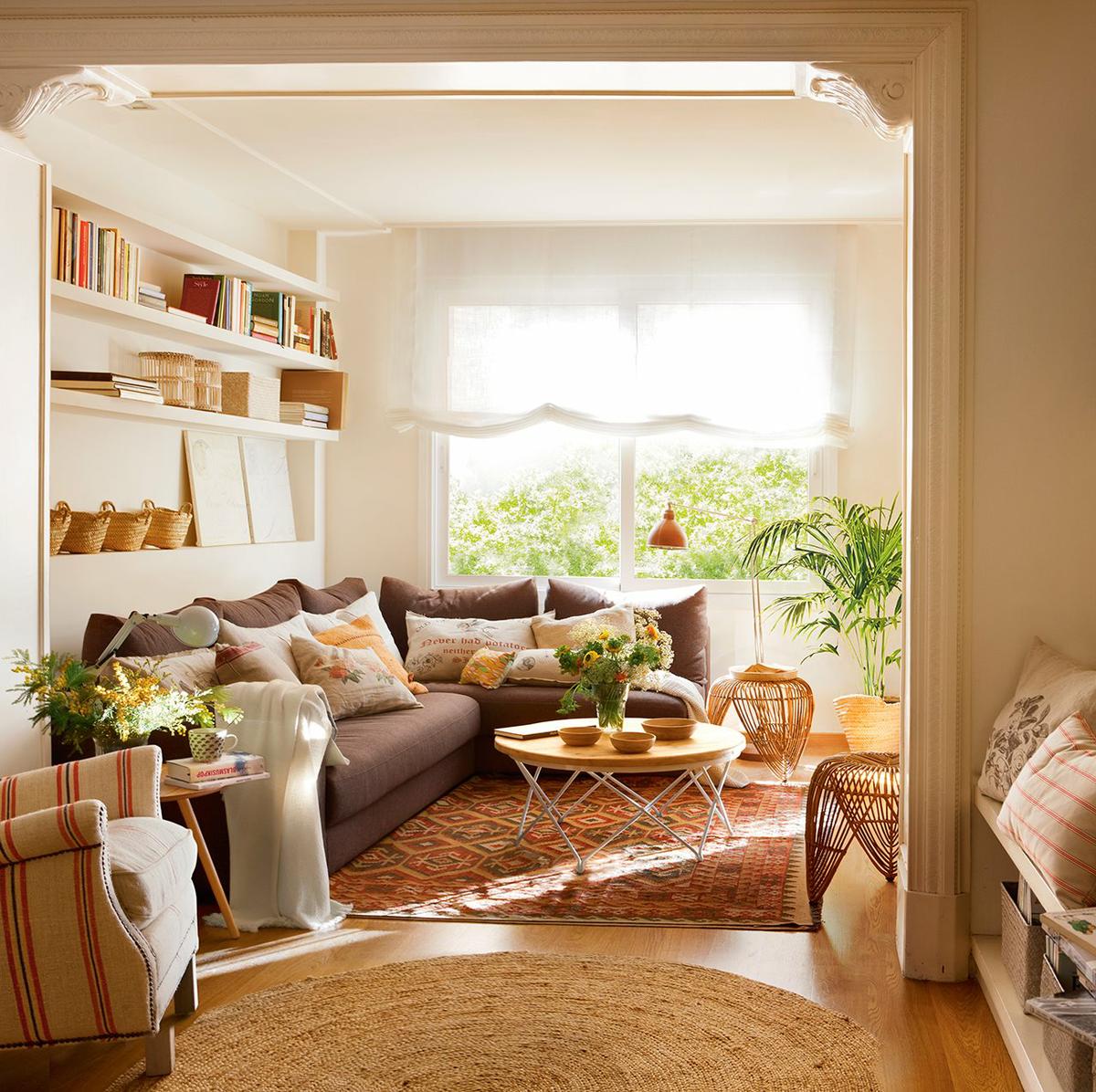 Vista del salón decorado con tonalidades tierra y baldas detras de sofá para hacer más funcional el espacio