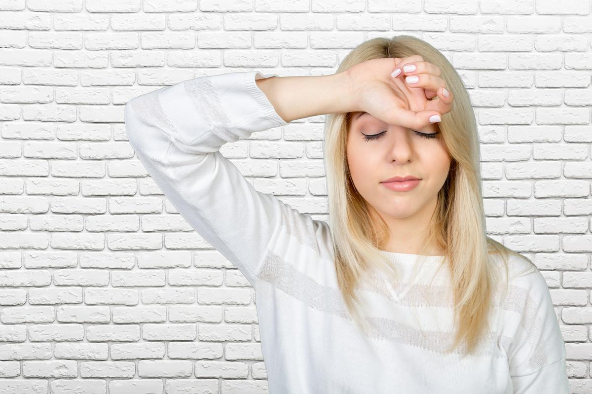 Depressed mature woman touching forehead and keeping eyes closed