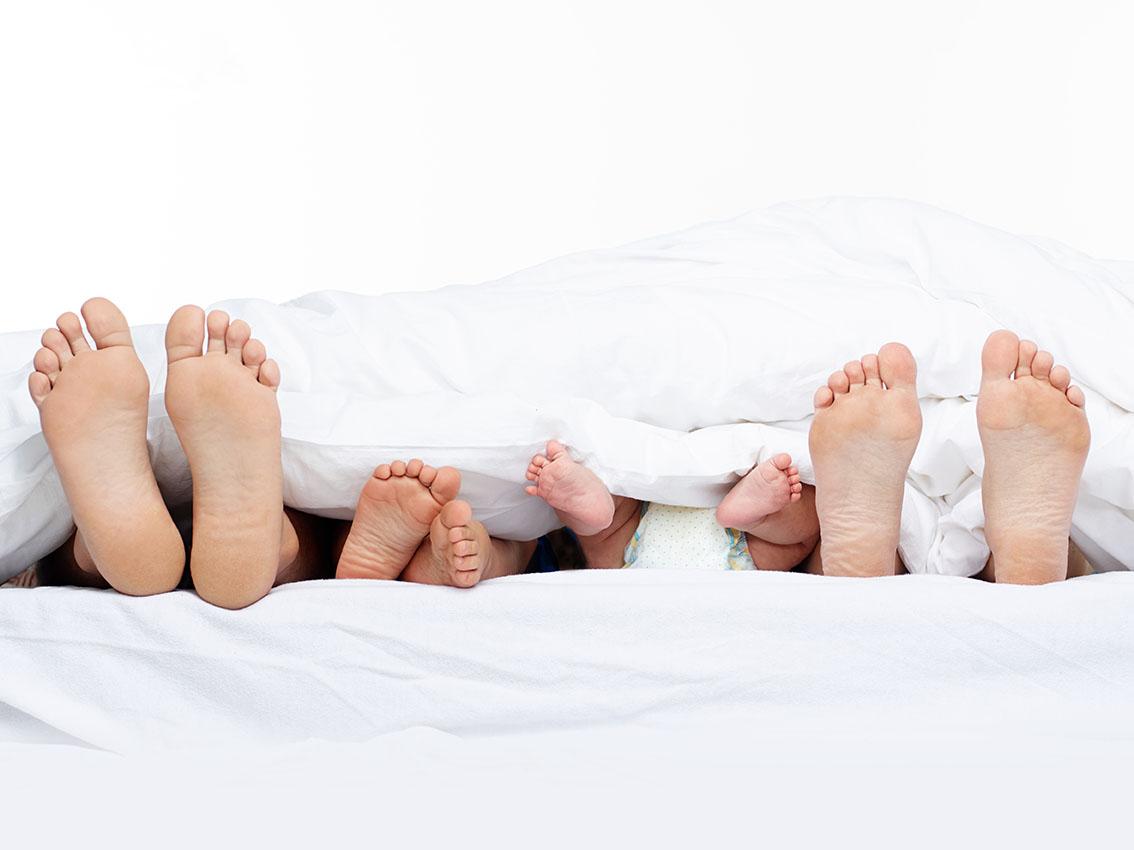 Feet of a family sticking out from the quilt