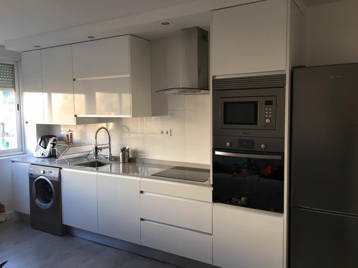 Frente de la cocina, alto brillo y electrodomésticos en gris y acero.