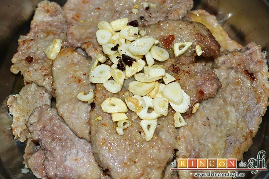Filetes de ternera al cava, echar sobre la carne los ajos y las guindillas