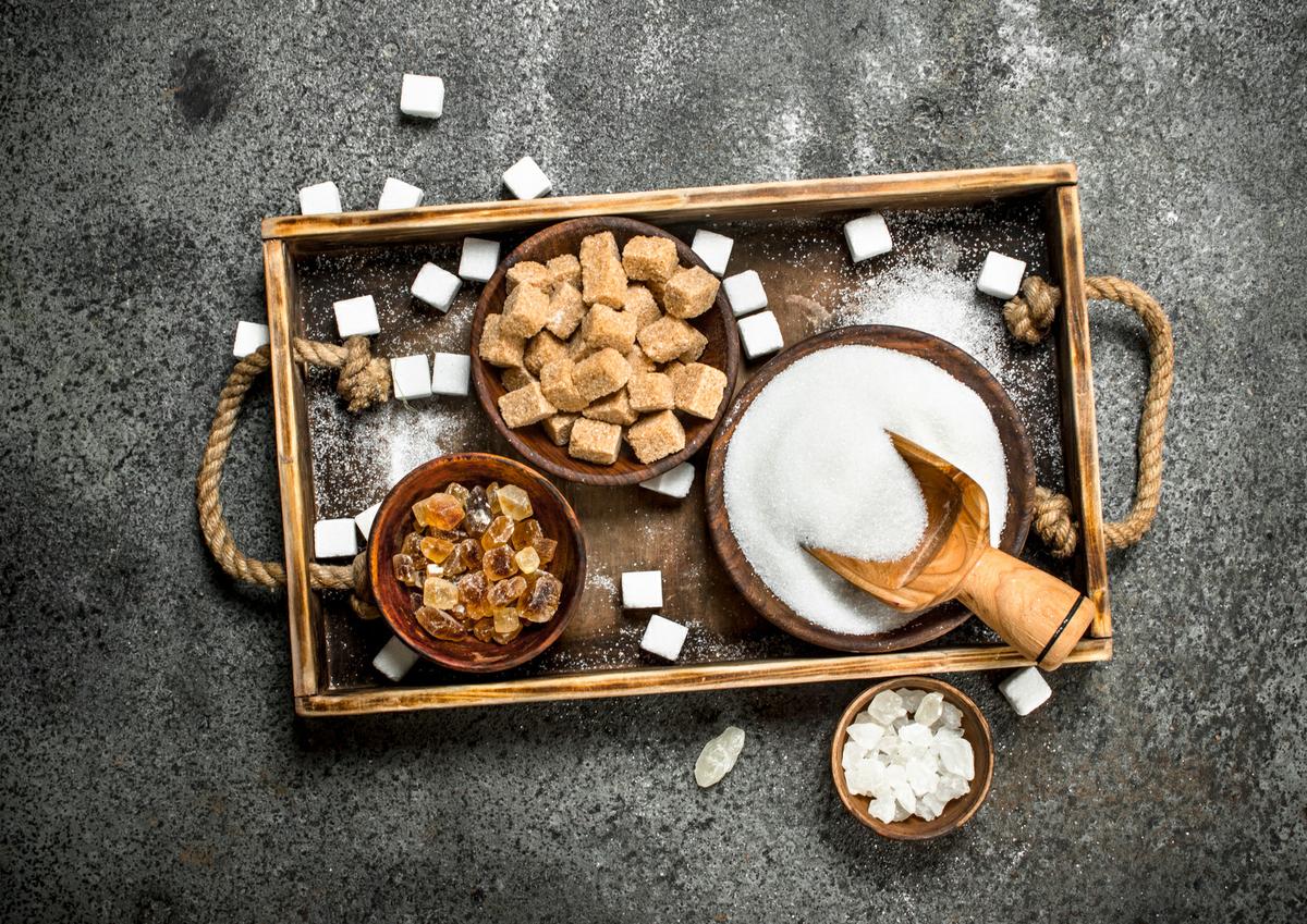 Different kinds of sugar in bowls on a tray. On a rustic background.