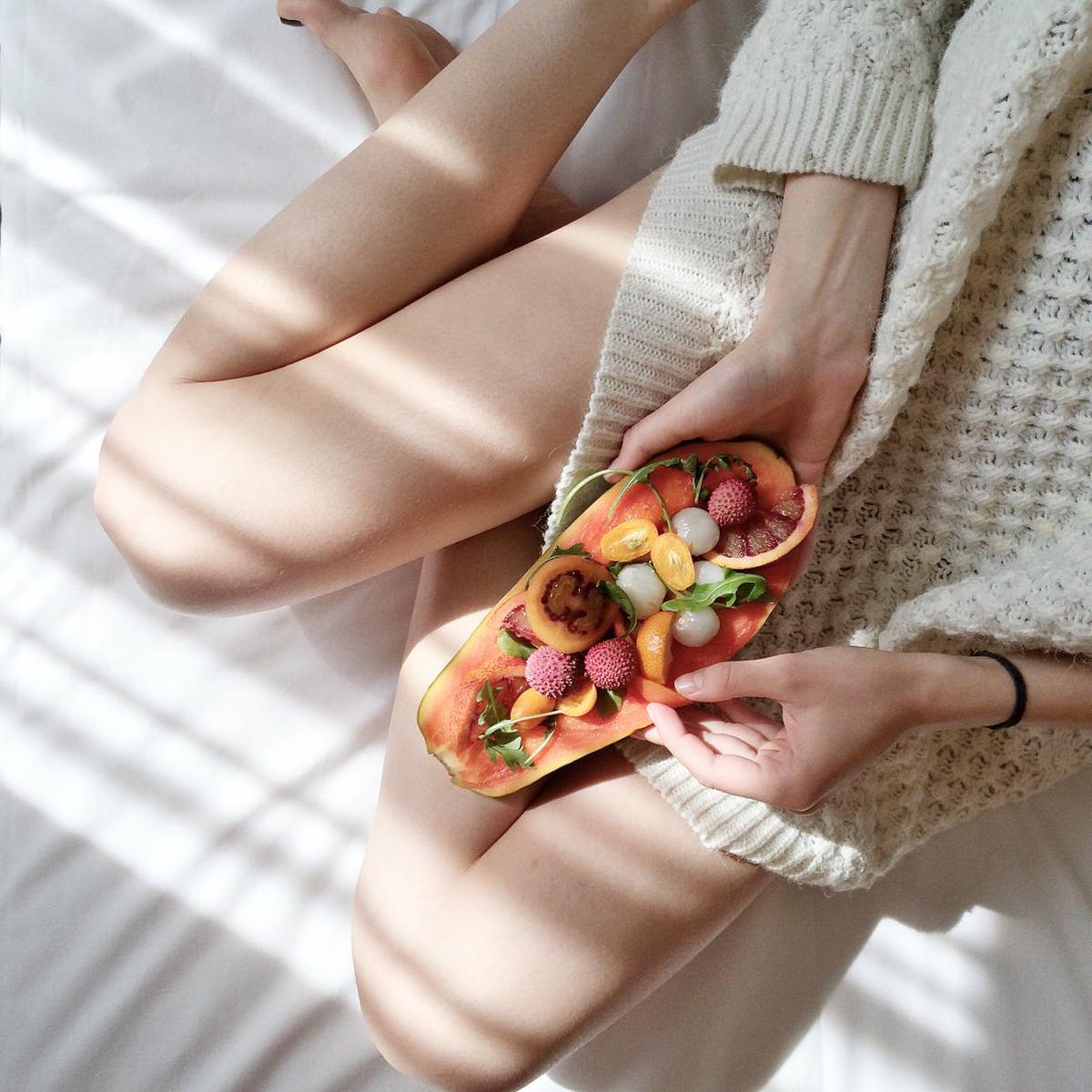 person holding papaya fruit on bed