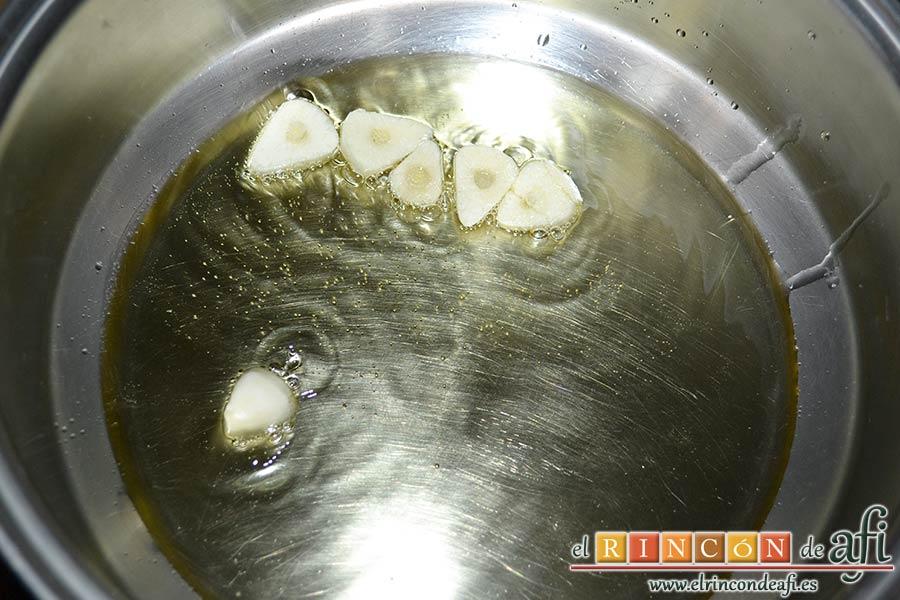 Chuletas de cerdo con alcaparras y anchoas, dorar el ajo laminado en un caldero con aceite de oliva
