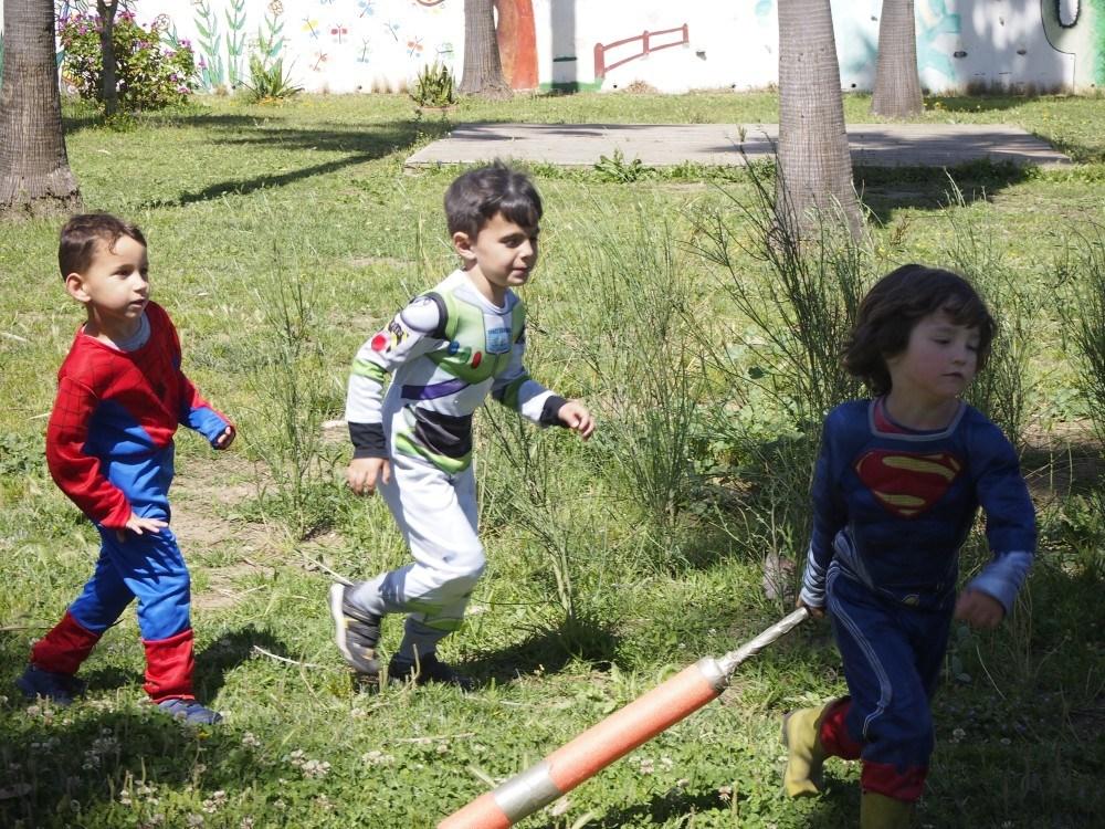 Niños disfrazados corriendo por la pradera de cesped en el parque