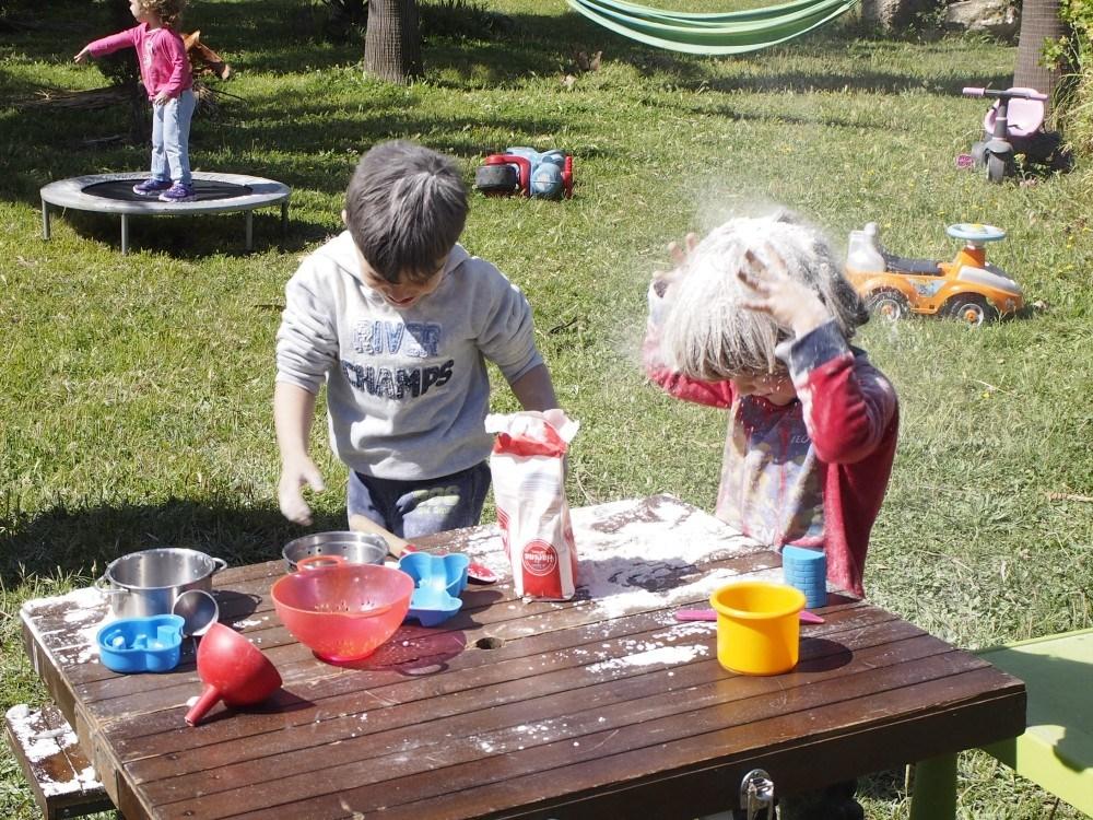 Niños echandose harina por encima de la cabeza en el grupo de juego exterior