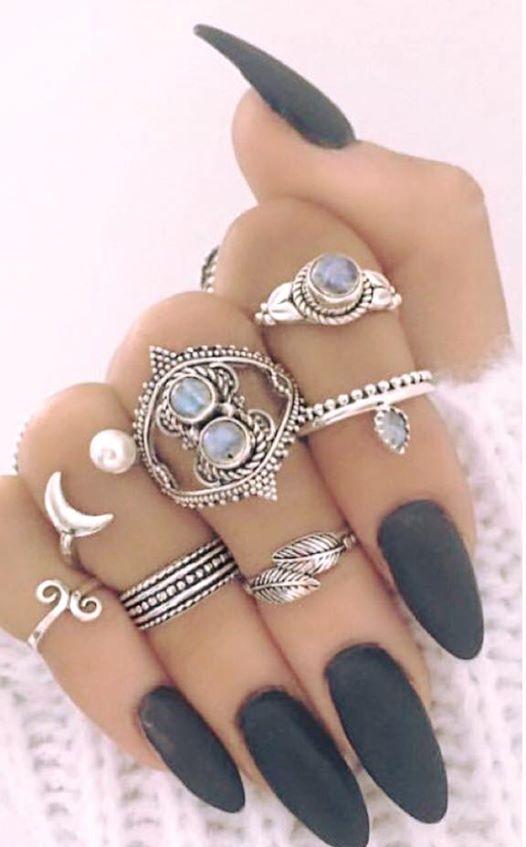 mano de mujer con uñas pintadas de oscuro y anillos