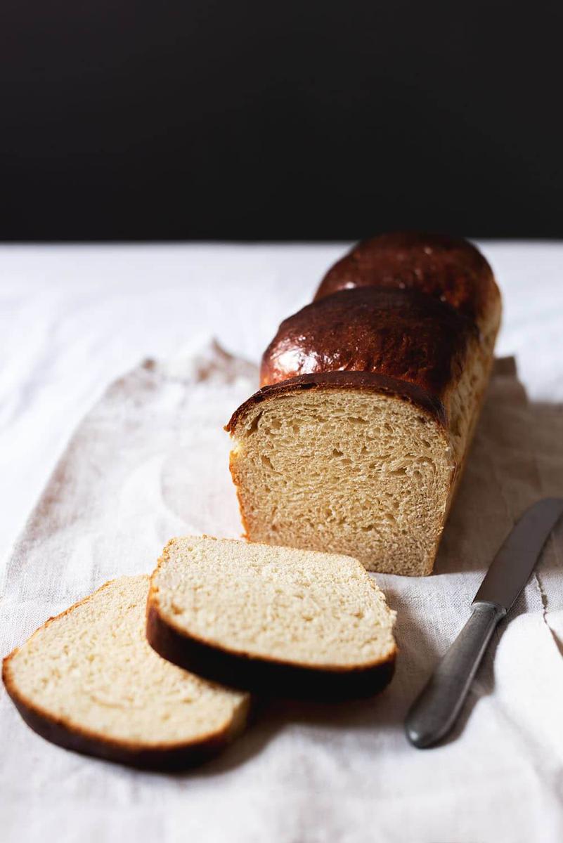 En una mesa está puesto un mantel blanco. Encima está el pan de brioche de la abuela cortada.