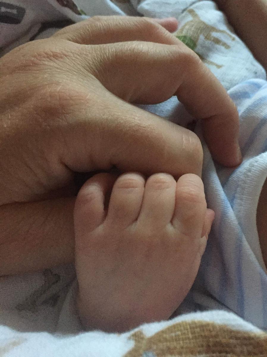 recién nacido coge la mano de su madre