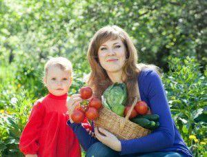 14341968-happy-woman-and-baby-with-vegetables-harvest-in-garden