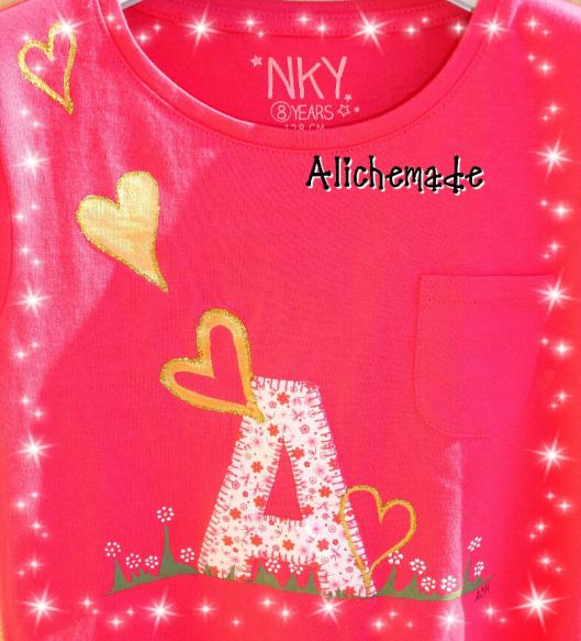 Detalles de la camiseta con inicial aplicada y corazones dorados pintados a mano.