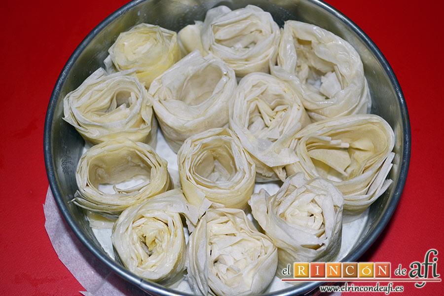 Tarta crujiente, seguimos haciendo rollitos con la masa filo y los vamos colocando en el molde