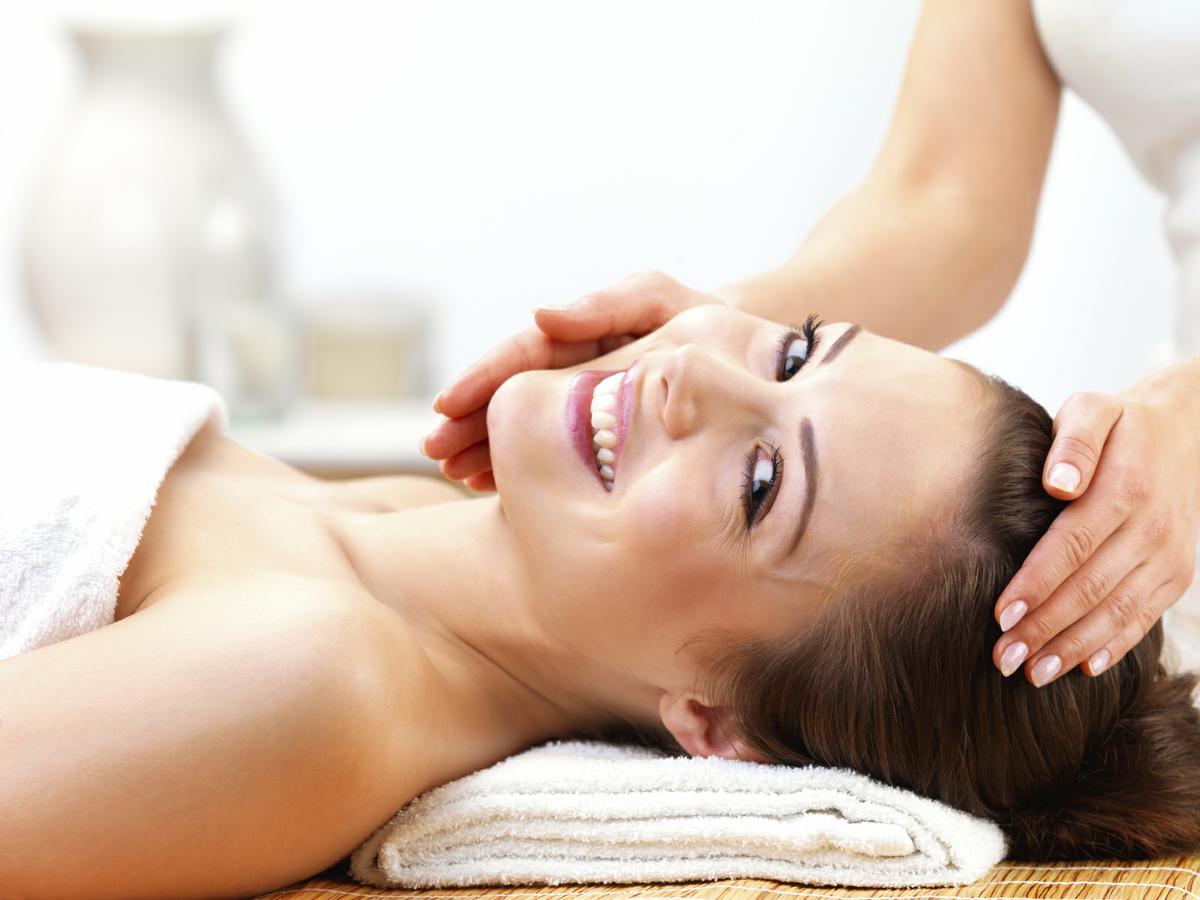 Portrait of a cheerful young female receiving facial massage