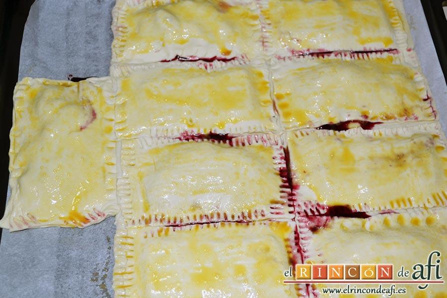 Empanadillas de cerezas y chocolate, pintar las láminas de hojaldre con el huevo batido ayudándonos de un pincel de cocina