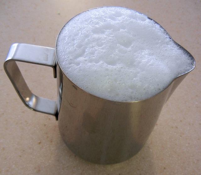 Foto de una jarra de acero inoxidable con espuma de leche