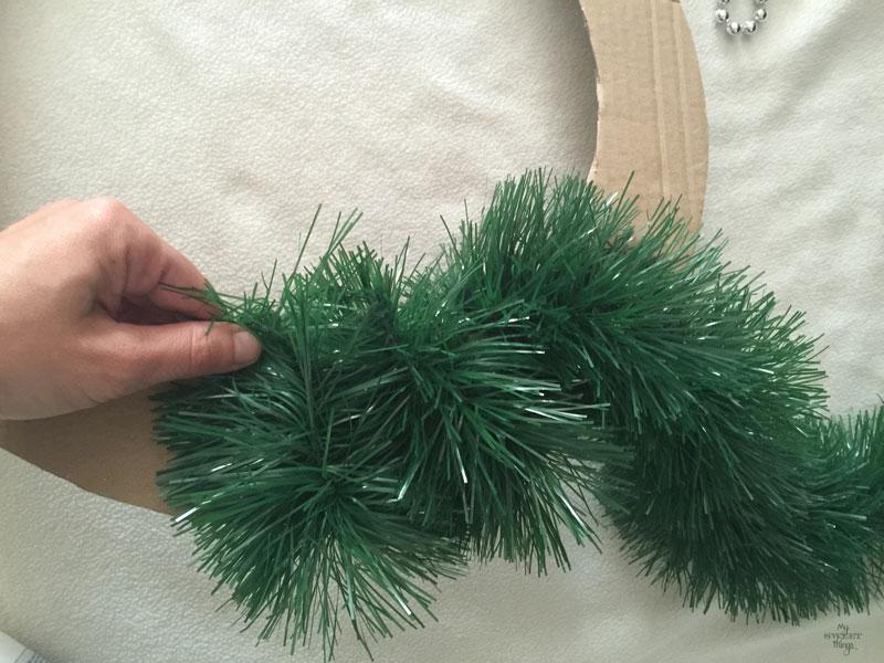 Cómo hacer una corona de Navidad casera fácil y elegante, usando cartón, piñas, nueces y una guirnalda | Via www.sweethings.net 