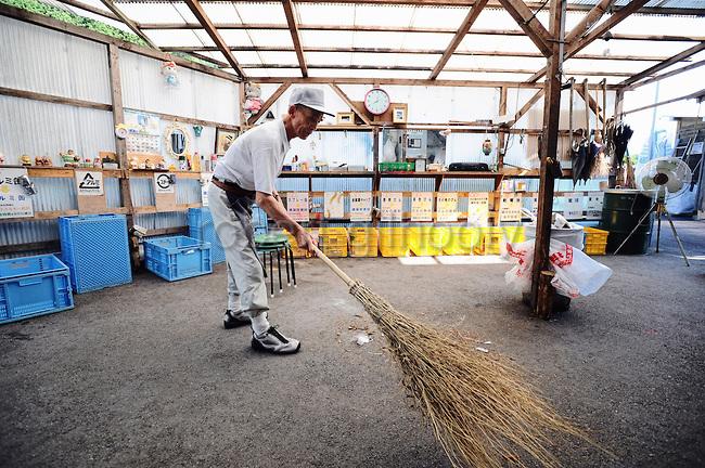 Masaru Goto, 73, sweeps up as part of his daily chores at the waste disposal site in central Kamikatsu Town in Shikoku, Japan on July 22, 2008. The town, whose residents number just over 2,000 people, has implemented a waste recycling policy that aims at eliminating waste entirely within the next 12 years and employs retired local residents to care for the waste disposal center. Photographer: Robert Gilhooly