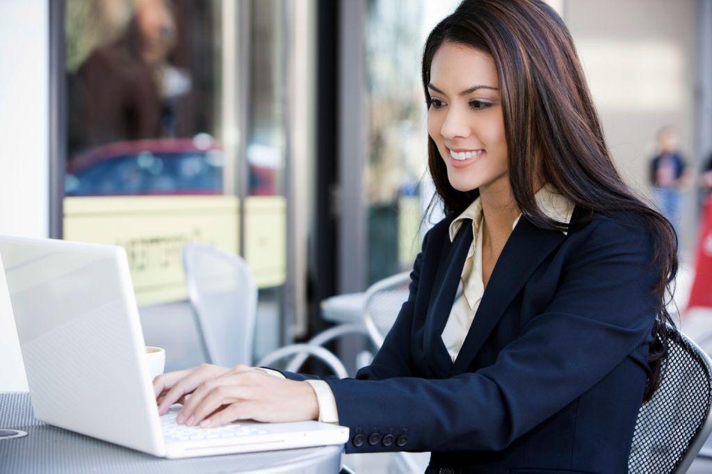 Mujer-sonriente-leyendo-un-email-en-su-portatil-en-la-mesa-de-su-oficina