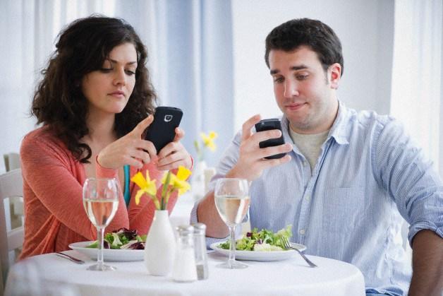 Jersey City, New Jersey, USA --- USA, New Jersey, Jersey City, Couple having dinner and text messaging --- Image by © Jamie Grill/Tetra Images/Corbis