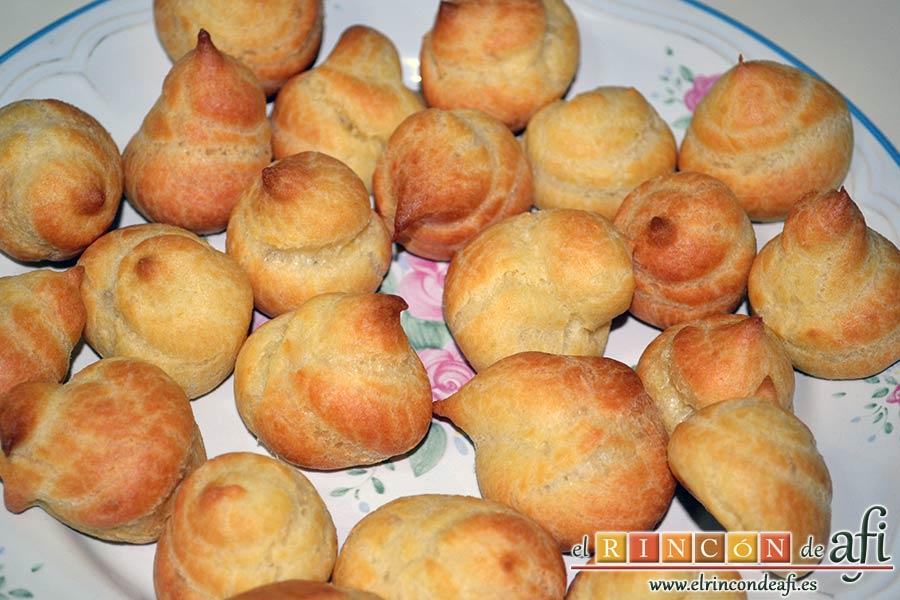 Profiteroles rellenos de nata (crema de leche) y cubiertos con chocolate, hornear hasta que estén dorados