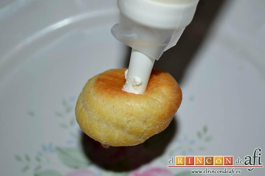 Profiteroles rellenos de nata (crema de leche) y cubiertos con chocolate, se puede rellenar los profiteroles por un agujero