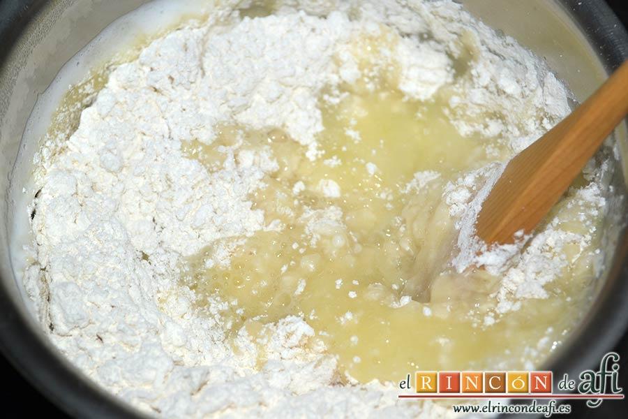 Profiteroles rellenos de nata (crema de leche) y cubiertos con chocolate, separar del fuego y añadir toda la harina de golpe