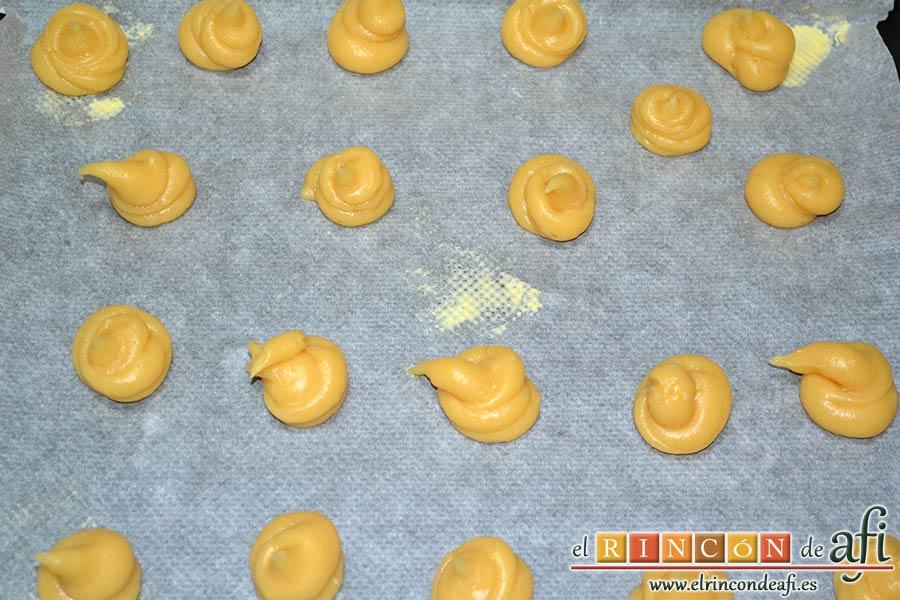 Profiteroles rellenos de nata (crema de leche) y cubiertos con chocolate, poner la masa en una manga pastelera con boquilla redonda y hacer montoncitos separados