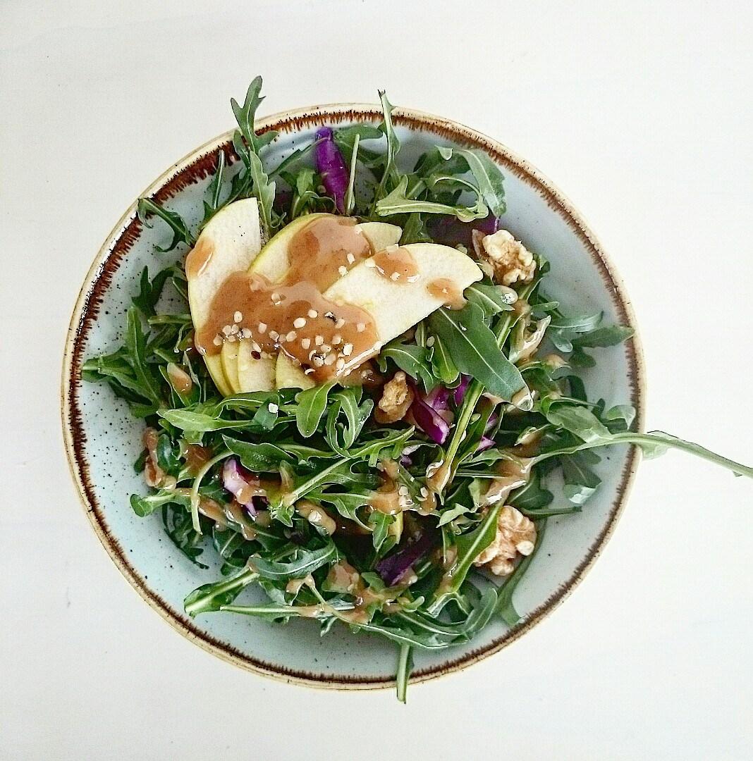 Ensalada de rúcola, manzana, col lombarda y nueces con salsa de crema de nueces de Amandíny naranja.