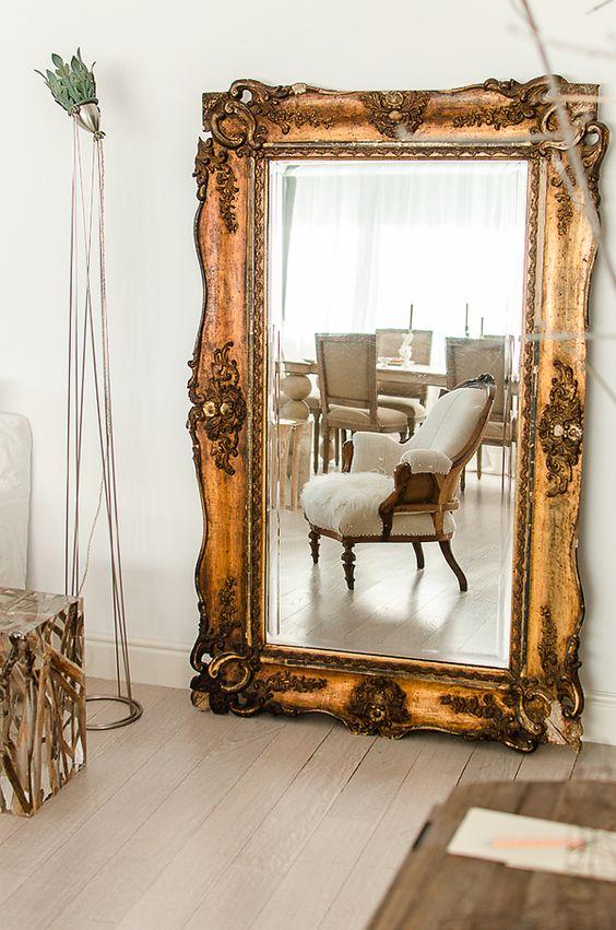 Espacio salón decorado con espejo grande con marco en oro viejo