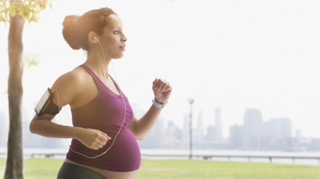 Pregnant mixed race woman power walking in park