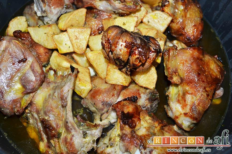 Cabrito estilo Afi, añadir a la carne las papas, la cabeza de ajo y la mitad del aceite de la fritura del cabrito