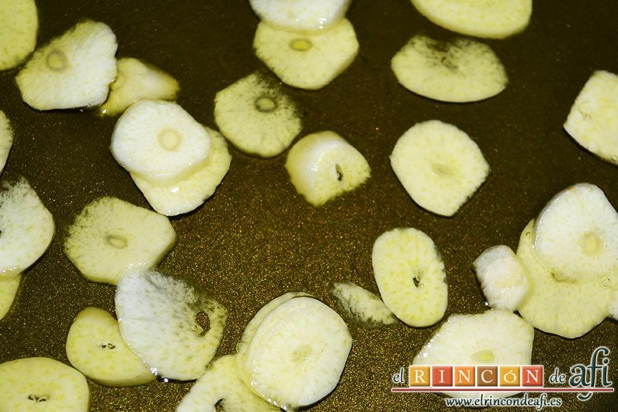 Acelgas con papas y refrito de ajos con jamón serrano, poner los ajos laminados en una sartén con aceite de oliva