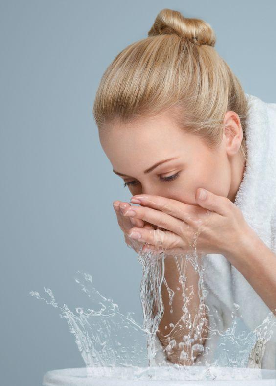 Young woman washing her face and hands with clean water in the morning