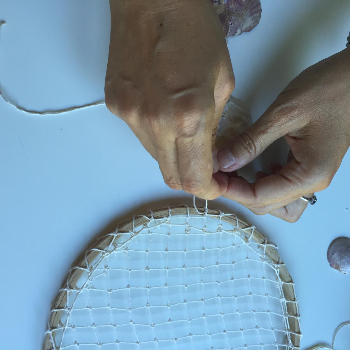 pasamos la concha por el agujero y atamos la cuerda al bastidor