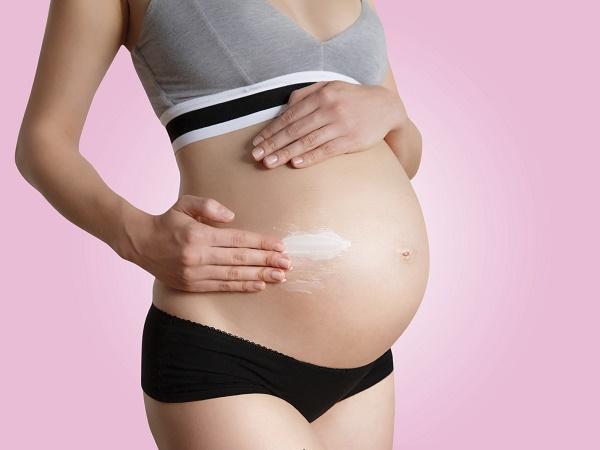 Pregnant woman skin care moisturizer cream on belly