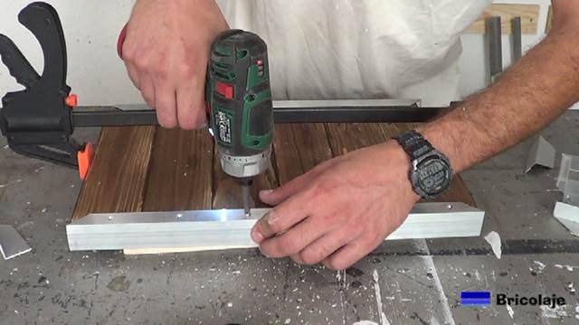 atornillando los agujeros para sujetar la madera de palé a los ángulos de aluminio