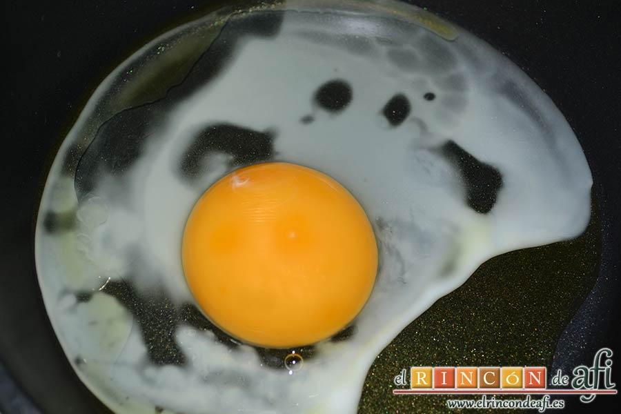 Papas fritas, huevos fritos, bacon y cebollas, freír el huevo en abundante aceite de oliva