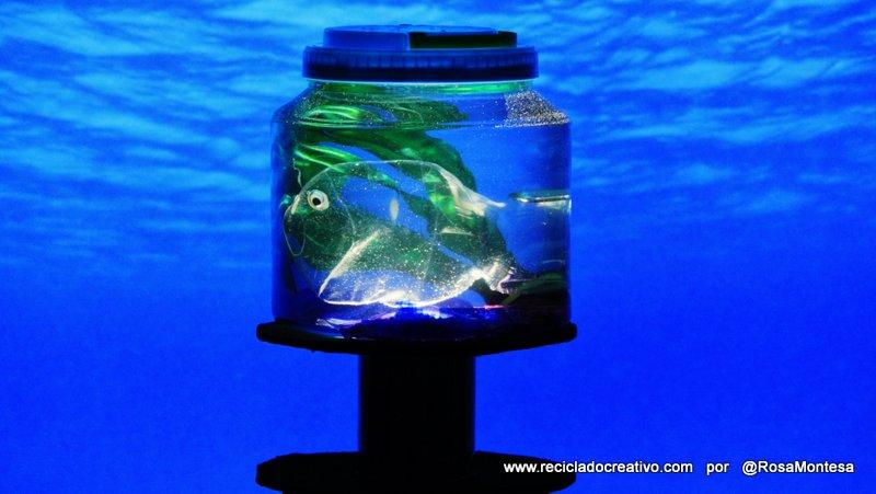 Pez hecho con una botella de plástico, dentro de una pecera con botellas de PET