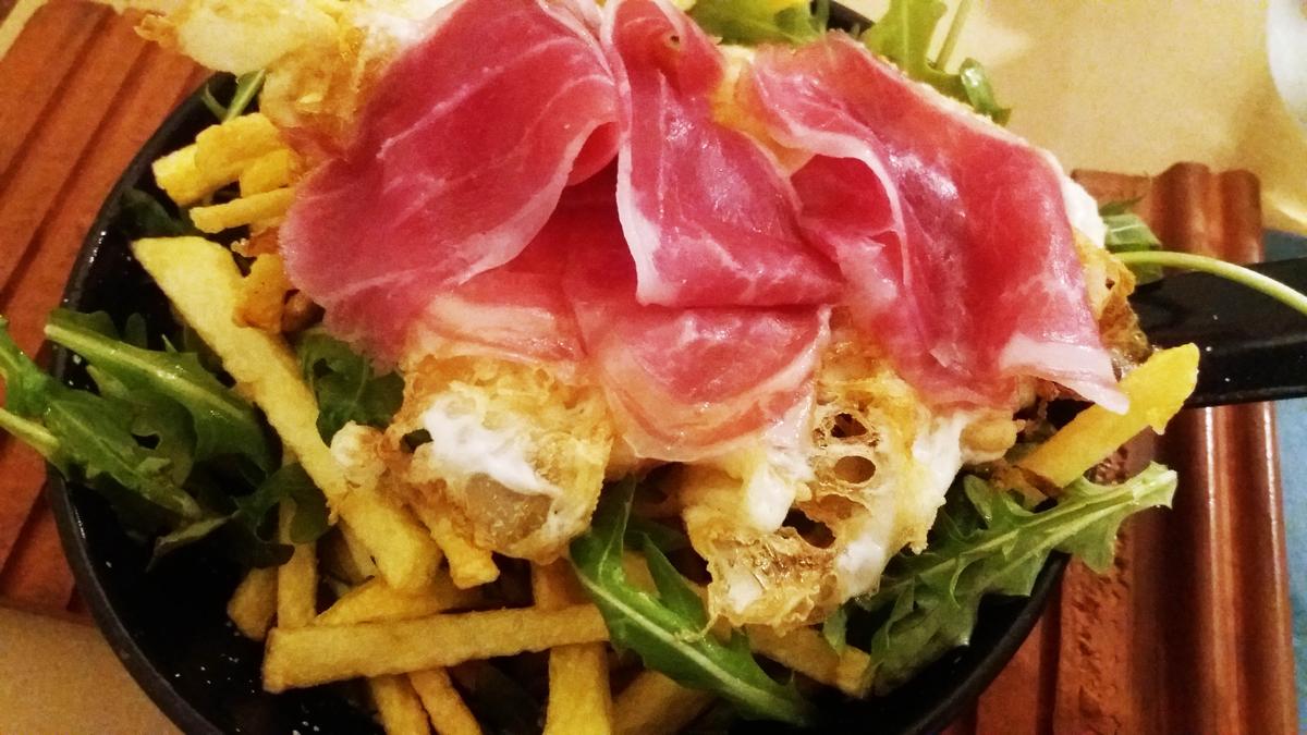 Huevos rotos con patatas, rúcula y jamón