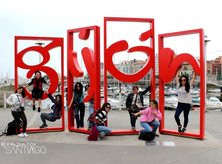 el equipo del camino posando en escultura con el nombre de Gijón