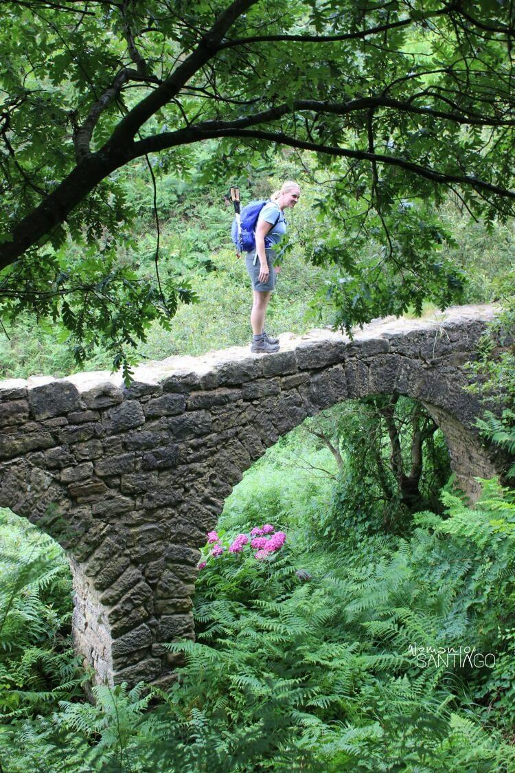 heidi encima de un puente de piedra rodeada de naturaleza