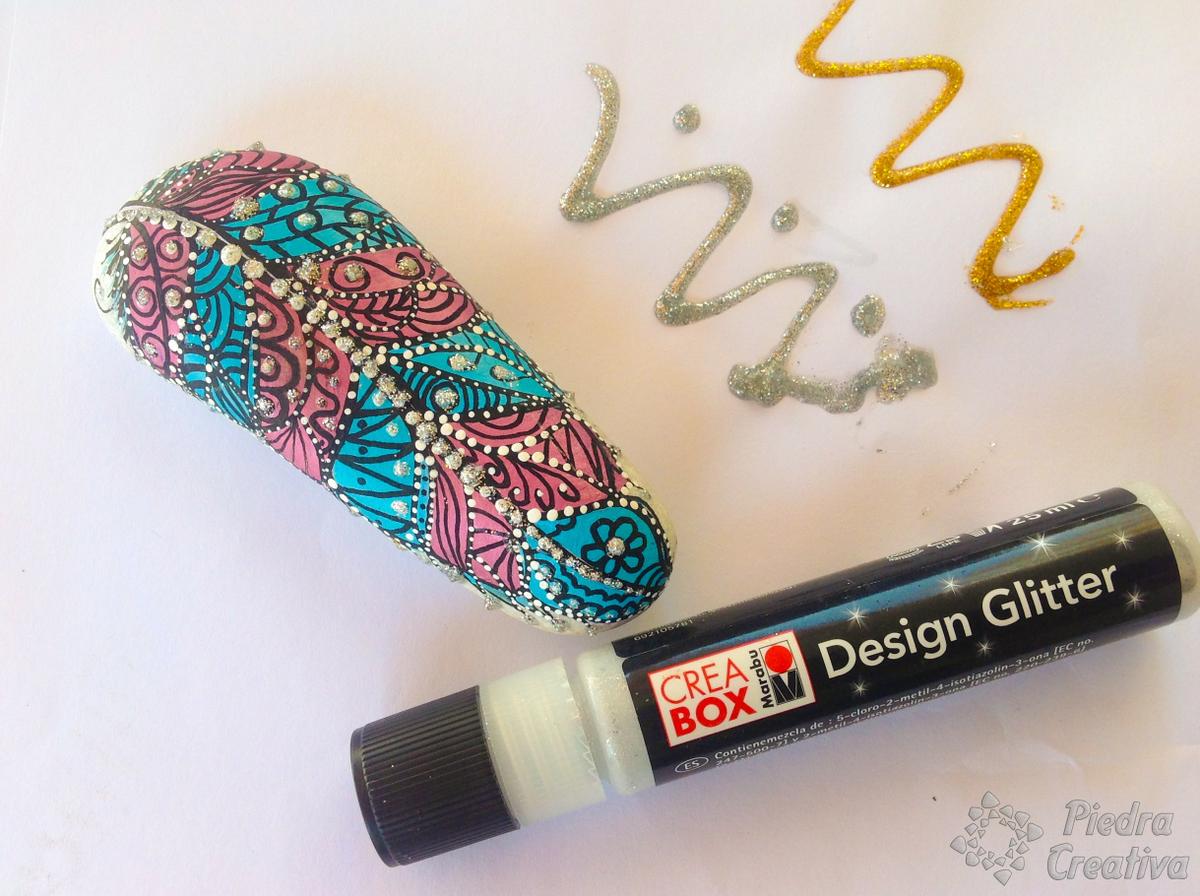 Pluma pintada en piedra con brillantina