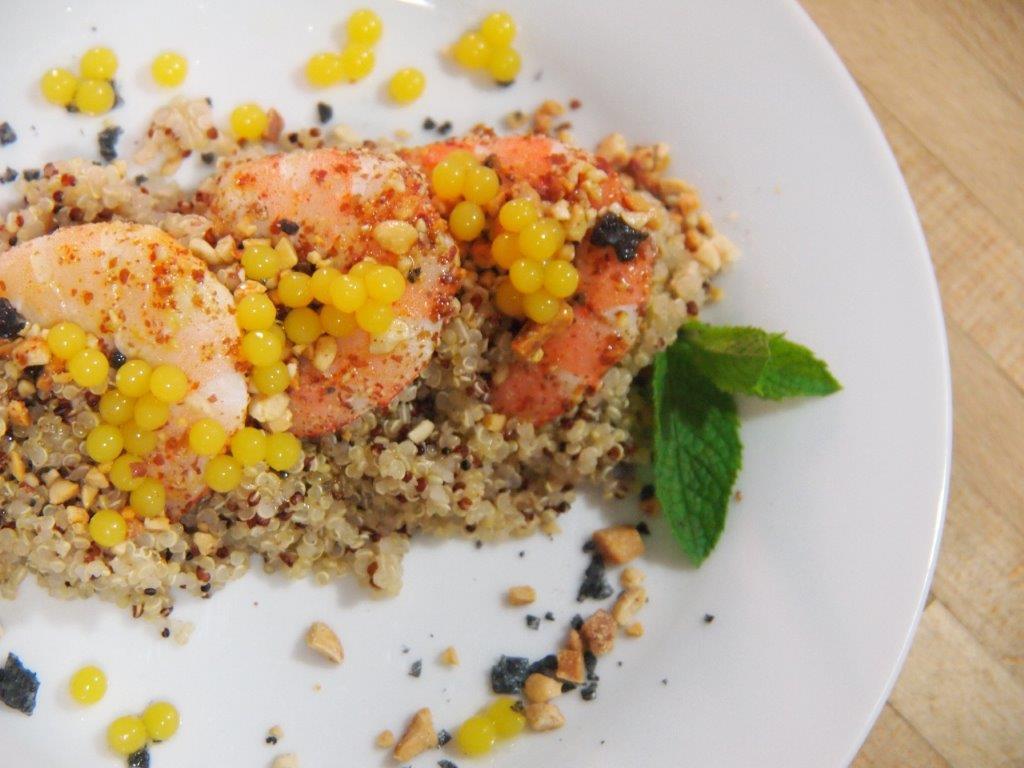 Quinoa aromatizada con langostinos y esferas de naranja emplatada